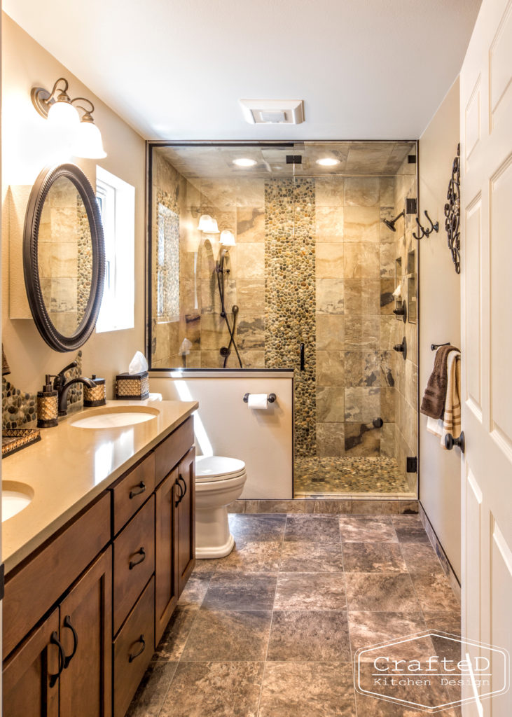 pebblies inspired bathroom remodel with wood cabinets and warm accent tile